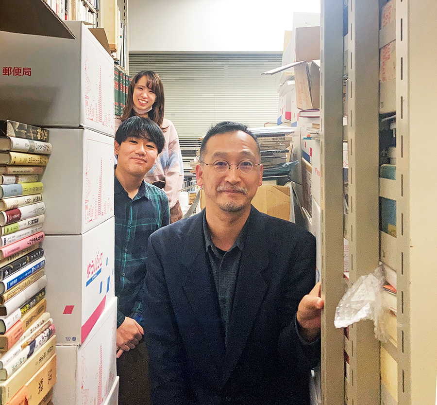 大量の本に囲まれた菊地暁先生(一番手前)の研究室にて